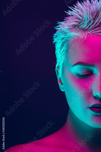 Serious. Portrait of female fashion model in neon light on dark studio background. Beautiful caucasian woman with trendy make-up and well-kept skin. Vivid style, beauty concept. Close up. Copyspace