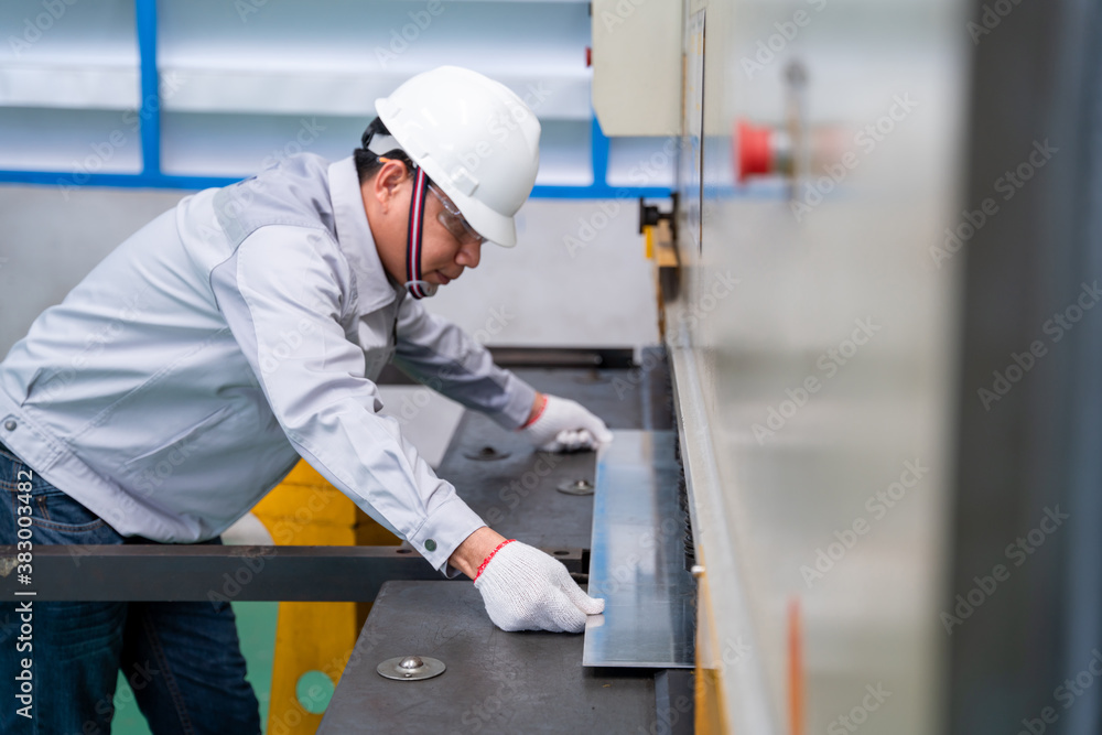 Asian technician worker wearing a safety suit and sheet Metal Shearing in industrial factory, Safety first concept.