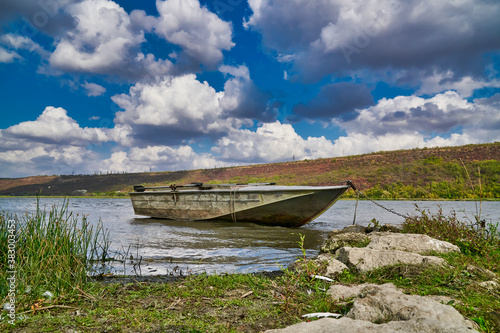 Fotografie, Obraz Old metal fishing boat moored in the shallow waters of the river