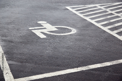 Parking spaces with lines of signs for disabled people on asphalt