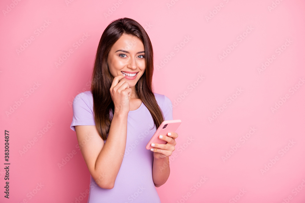 Portrait of girlish smiling girl hold smartphone touch cheek dressed violet t-shirt isolated on pink color background Portrait of girlish smiling girl hold smartphone touch cheek dressed violet t-shirt isolated on pink color background