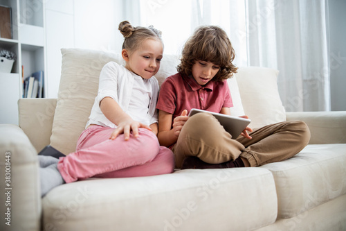Kids playing at the digital tablet at the sofa