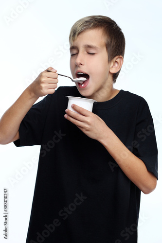 Boy eating yogurt isolated on white background