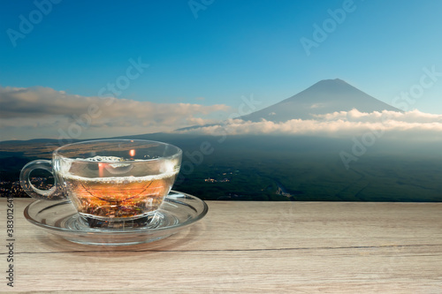 hot tea cup on a wooden table with fuji san mountain and city top view scenery