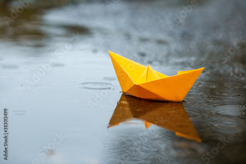 Paper handmade boat toy on a puddle in a rain