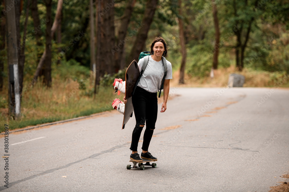 Fototapeta premium cheerful woman in white t-shirt riding skateboard with wakeboard in her hand.