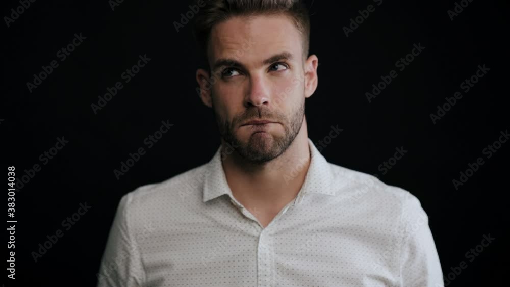 A serious young man is thinking about something standing isolated over black background A serious young man is thinking about something standing isolated over black background