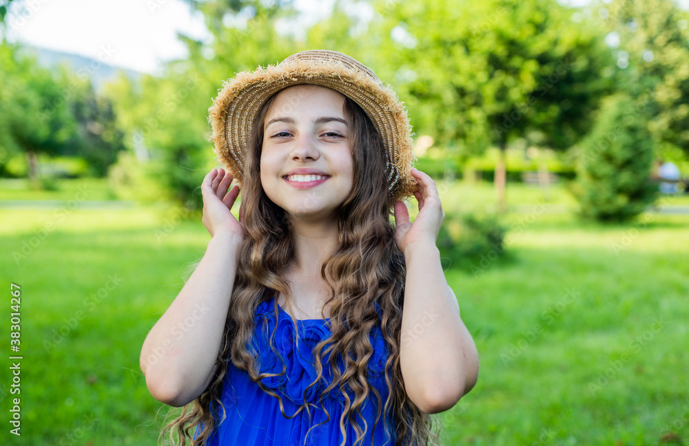 Optimistic smiling girl enjoying sunny summer day in park