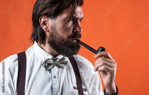 charisma. confident and elegant man in classical wear smoke pipe. masculinity and charisma. formal male smokier. old fashioned bearded hipster smoking pipe. trendy man in suspenders and bow tie photo