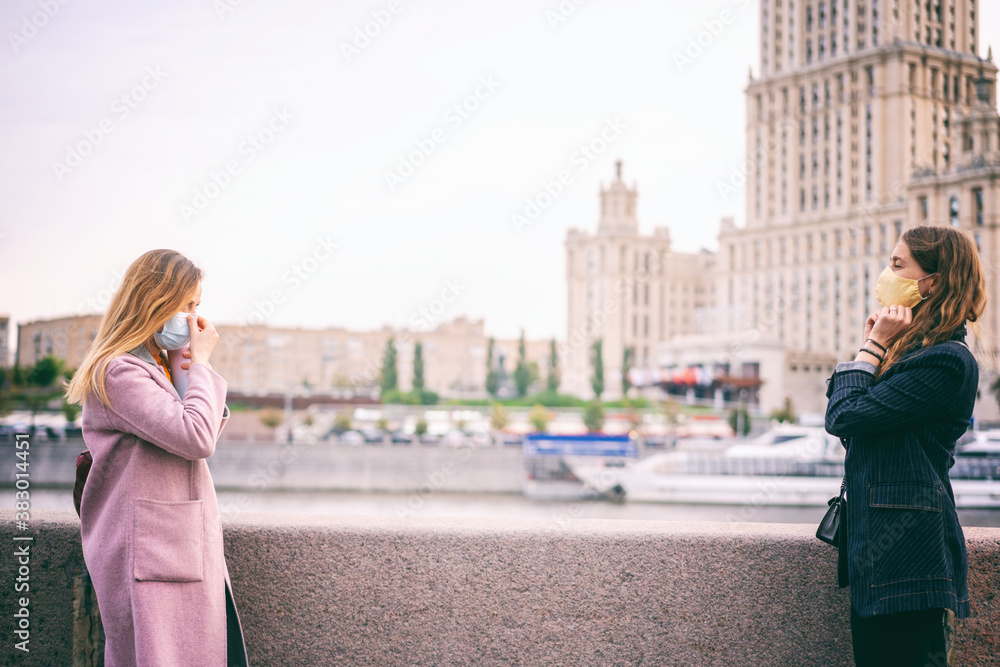 Two young women in protective masks walking in city of Moscow, social distance during the COVID 19 pandemic, second wave