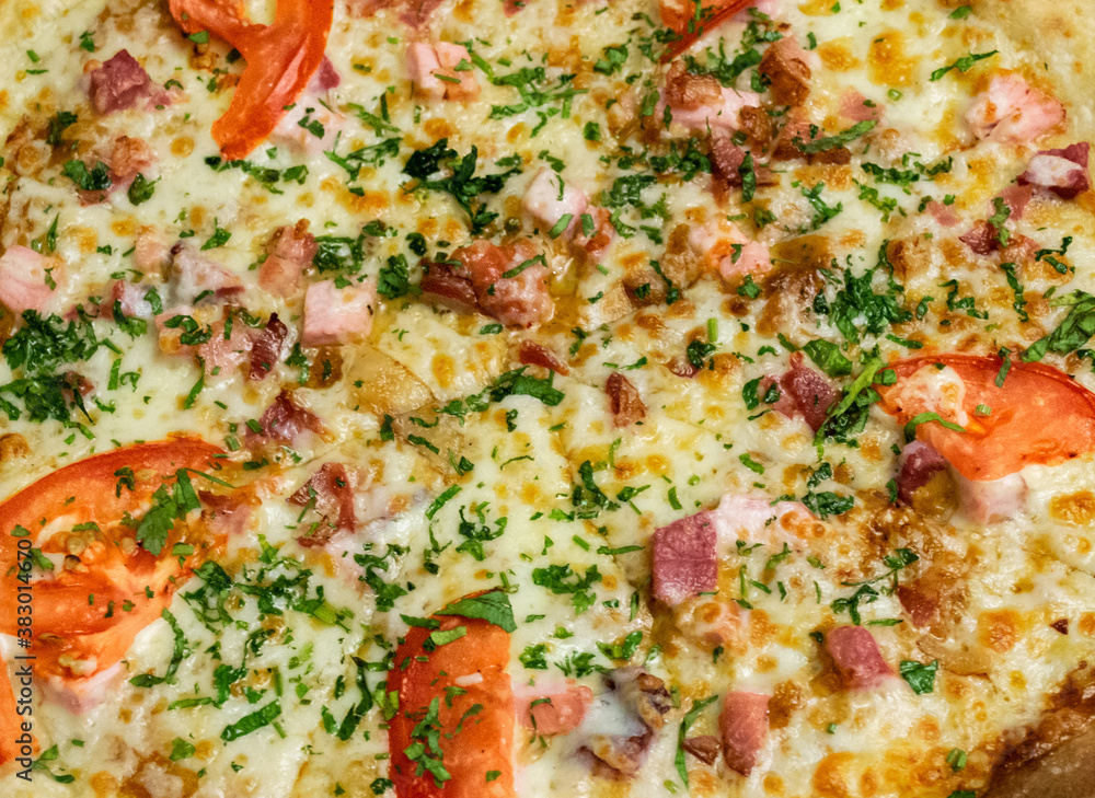 Close-up of pizza with ham, cheese, tomatoes and herbs and bacon. Food background Close-up of pizza with ham, cheese, tomatoes and herbs and bacon. Food background