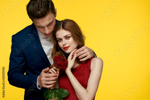 lovers man and woman with a red rose in their hands hugging on a yellow background romance relationship love family