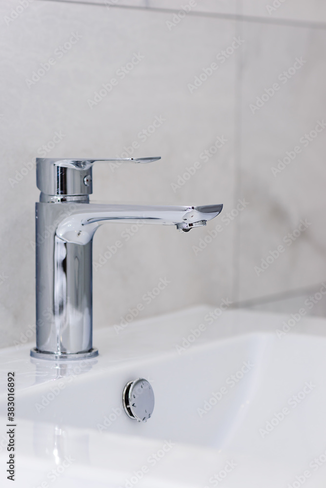 Faucet with a sink in the bathroom on a background of gray tiles. Renovation in the bathroom. Faucet with a sink in the bathroom on a background of gray tiles. Renovation in the bathroom.