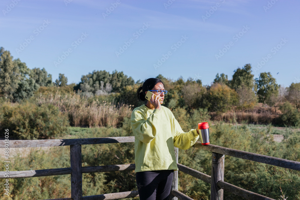woman talking on the phone on walkway in nature
