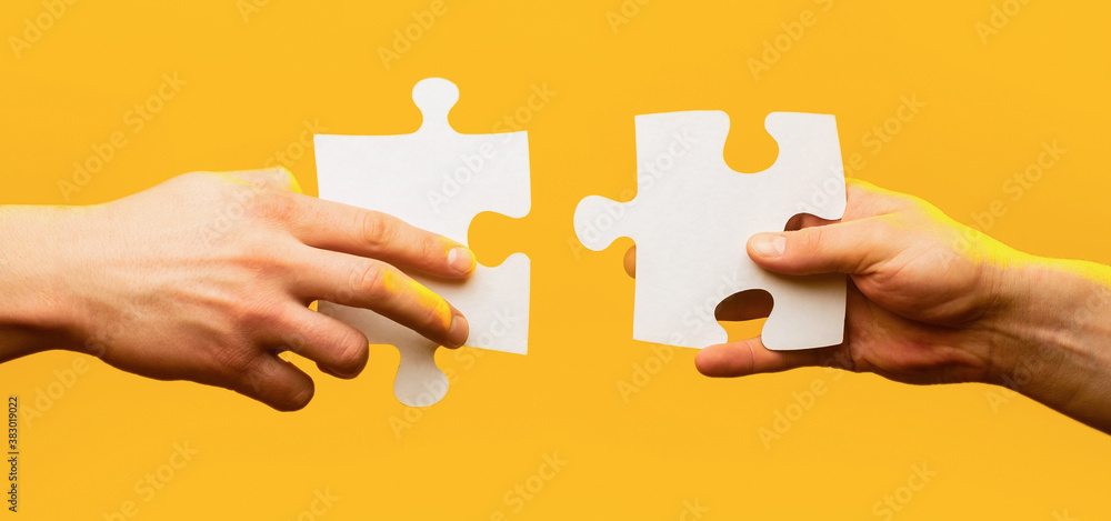 Two hands trying to connect couple puzzle piece on yellow background.  Teamwork concept. Holding puzzle. Closeup hand of connecting jigsaw puzzle.  Business solutions, success and strategy concept Stock Photo | Adobe Stock