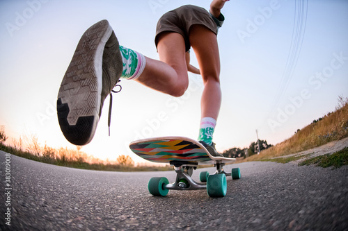 low angle view of girl who is riding on skateboard on the asphalt. photo
