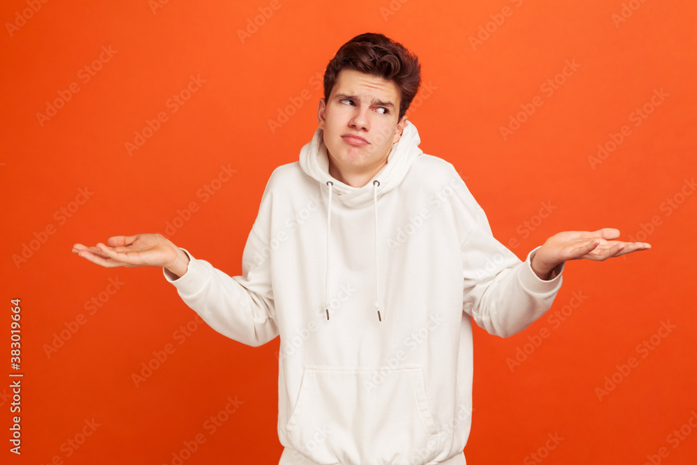 Don't know. Young doubtful man with cool hairdo shrugging shoulders, unknown information, confused with situation, careless. Indoor studio shot isolated on orange background Don't know. Young doubtful man with cool hairdo shrugging shoulders, unknown information, confused with situation, careless. Indoor studio shot isolated on orange background
