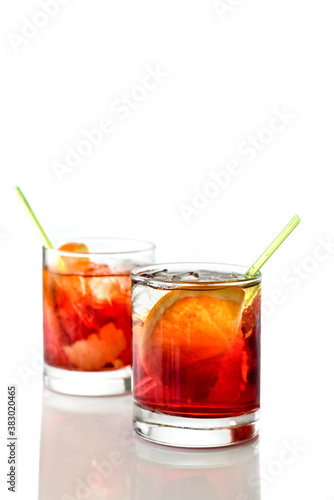 Negroni cocktail with ice cubes and orange slices in glass with straw isolated on white.Space for text