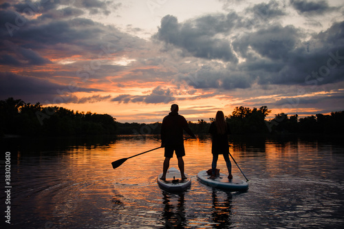 Schilderij op canvas romantic view on man and woman on sup boards floating on river