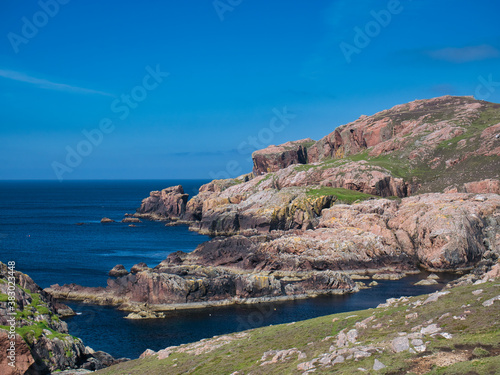 Red granite cliffs on Muckle Roe, Shetland, UK - these rocks are of the Muckle Roe Intrusion - granite, granophyric - igneous bedrock formed 359 to 383 million years ago in the Devonian Period. photo