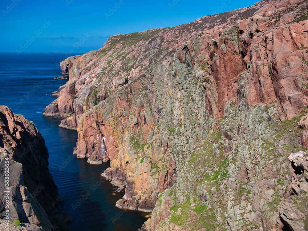 Red granite cliffs on Muckle Roe, Shetland, UK - these rocks are of the Muckle Roe Intrusion - granite, granophyric - igneous bedrock formed 359 to 383 million years ago in the Devonian Period. Red granite cliffs on Muckle Roe, Shetland, UK - these rocks are of the Muckle Roe Intrusion - granite, granophyric - igneous bedrock formed 359 to 383 million years ago in the Devonian Period.