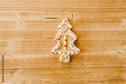 Christmas cookies decorated with icing and sprinkles on a wooden texture.