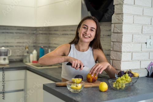 beautiful happy woman on kitchen making fruits salad