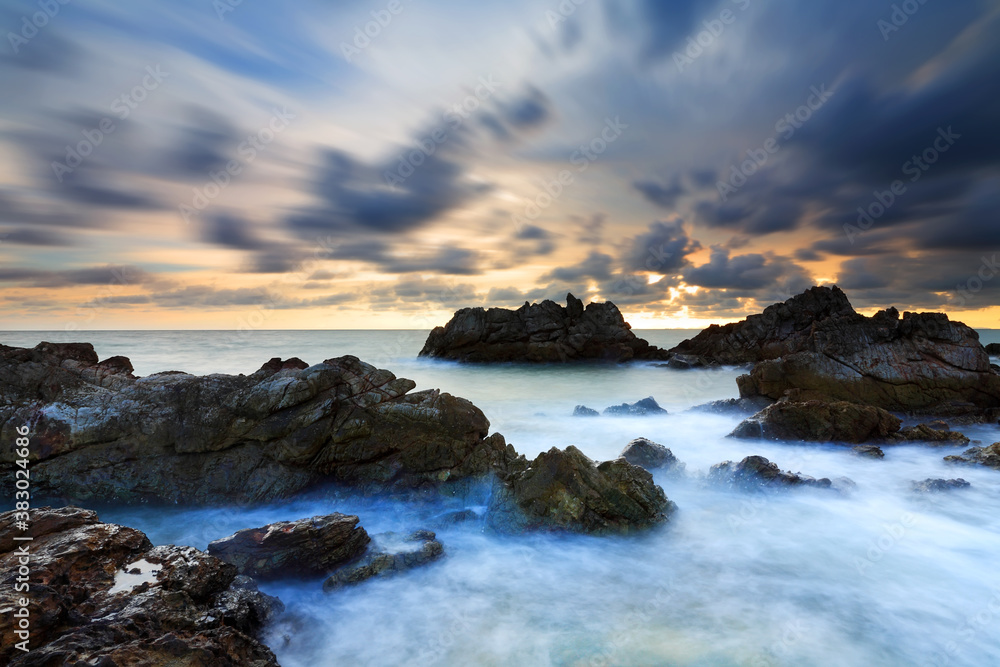 Long exposure of sea wave impact the stone  with clouds moving on beach in the sunset time, Eastern of Thailand