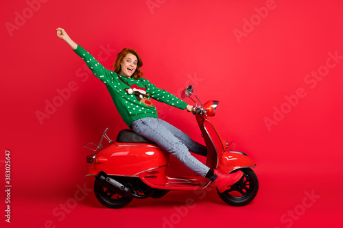 Photo portrait of happy bike driver celebrating wearing green sweater isolated on vivid red colored background