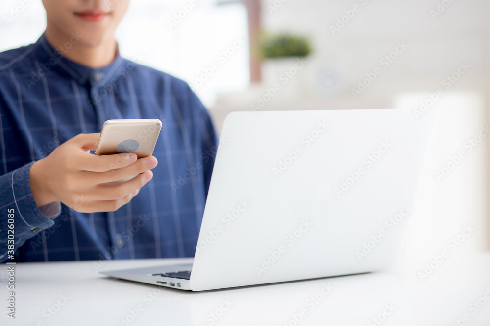 Closeup hand of young man working laptop computer and reading smartphone on internet online on desk at home, freelance male using phone with social media, business and communication concept. Closeup hand of young man working laptop computer and reading smartphone on internet online on desk at home, freelance male using phone with social media, business and communication concept.