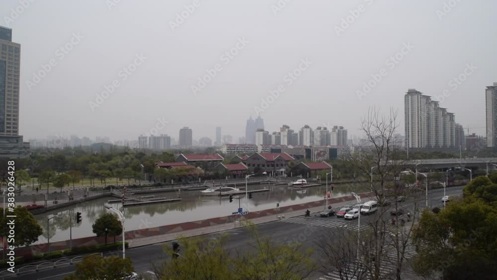 Intersection in Shanghai China on Cloudy Day with car traffic going by and river in Background Intersection in Shanghai China on Cloudy Day with car traffic going by and river in Background