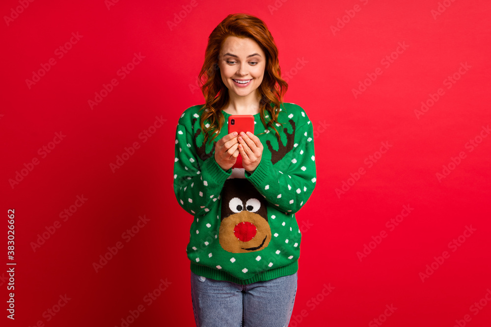 Photo portrait of smiling woman holding phone in two hands isolated on vivid red colored background Photo portrait of smiling woman holding phone in two hands isolated on vivid red colored background