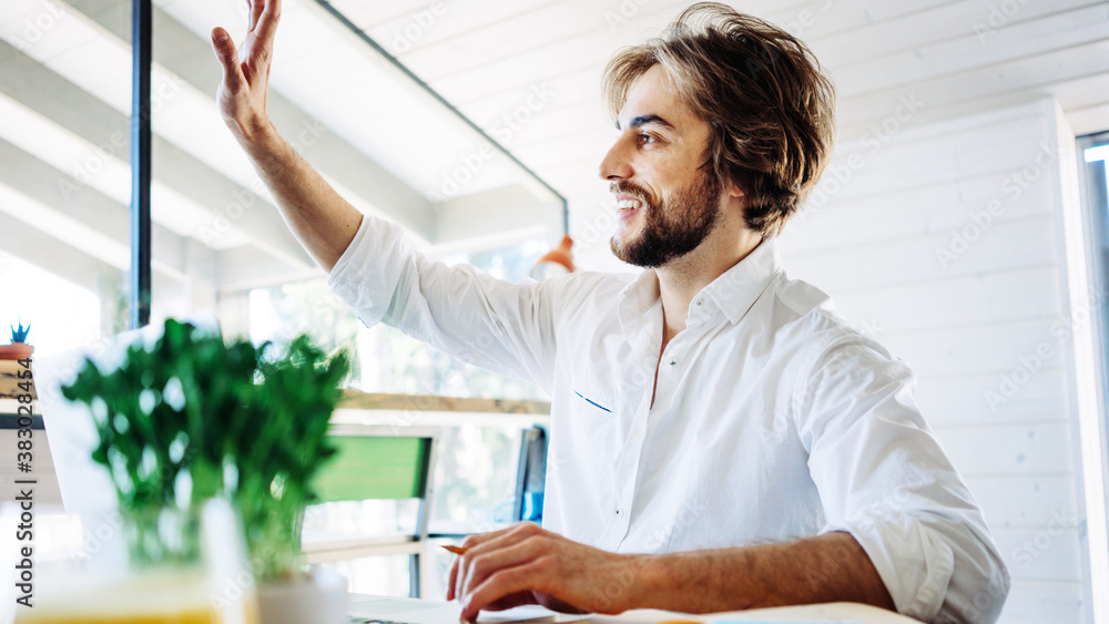 Obraz premium Handsome man with stubble sitting at home and working remote using laptop, greeting partner. Private house workplace