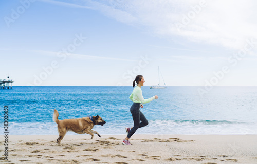 Happy woman running with dog on seashore
