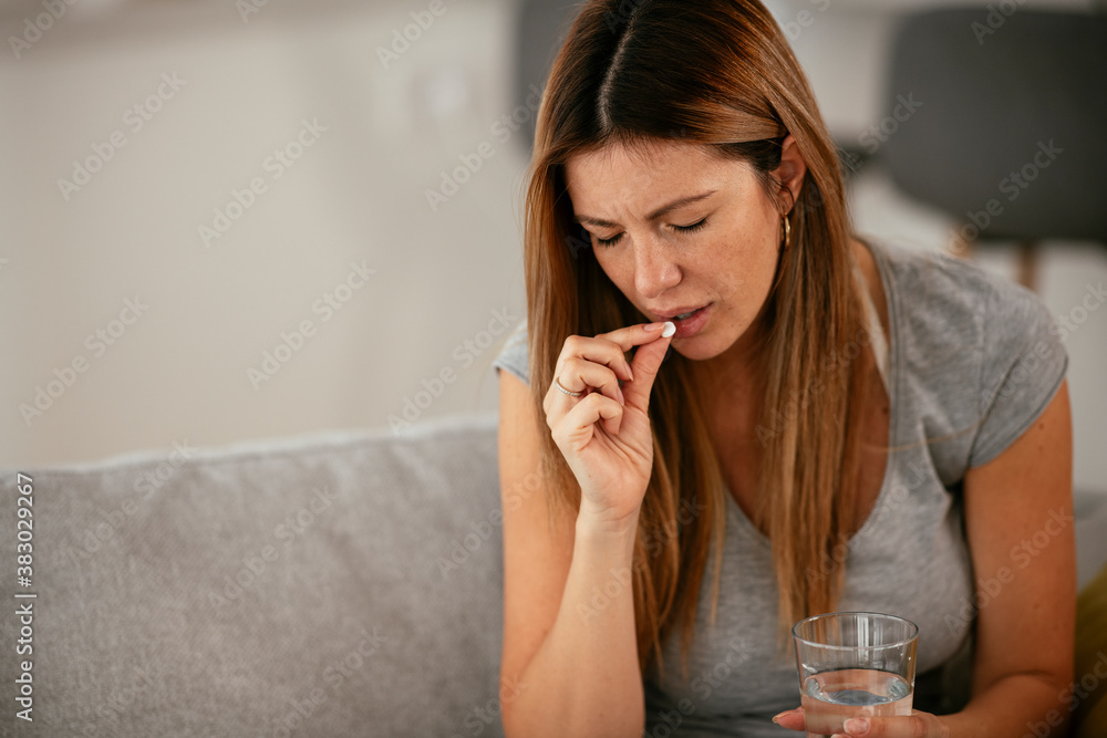 Young woman sick in bed holding glass of water. Young woman sick in bed holding glass of water.