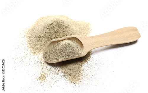Milled white pepper powder, peppercorn pile with wooden spoon isolated on white background