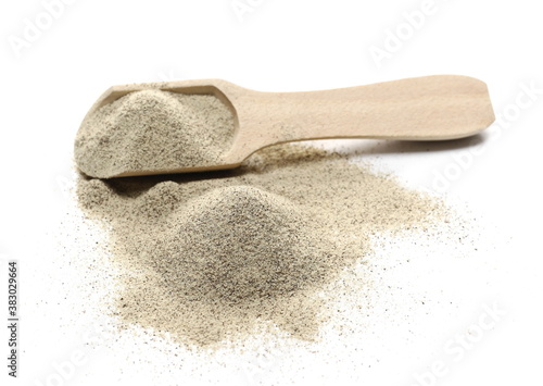 Milled white pepper powder, peppercorn pile with wooden spoon isolated on white background