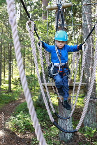 Boy overcoming hanging ropes obstacle in adventure park
