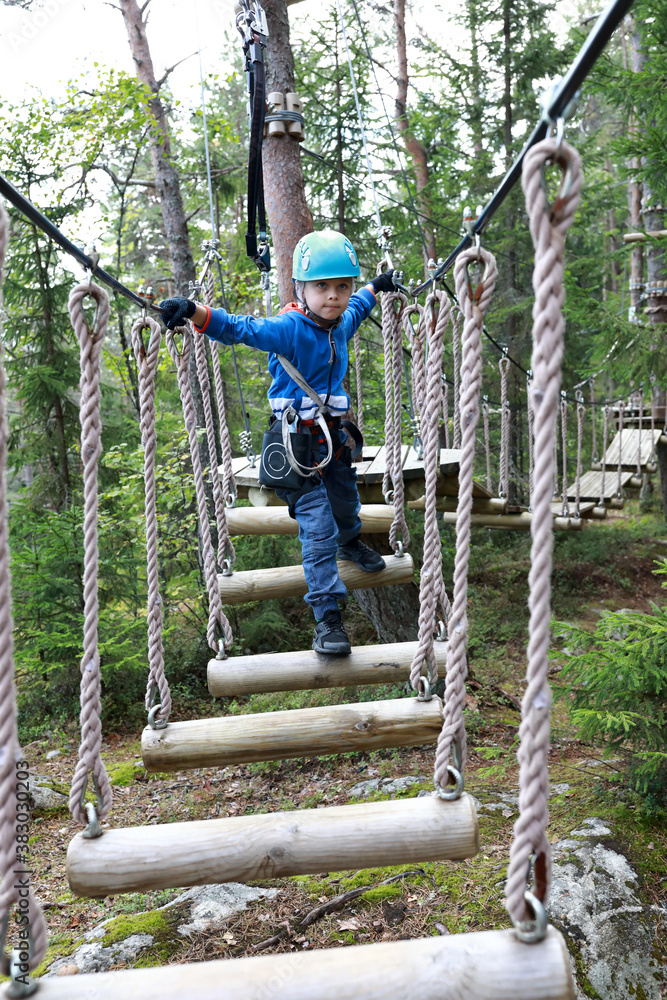 Child overcoming swinging logs obstacle in adventure park