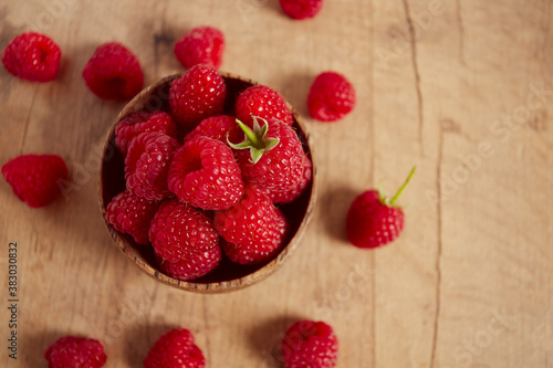 raspberries in a bowl on wooden surface
