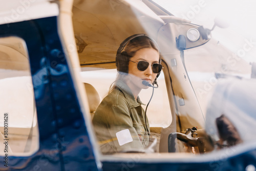 Canvastavla Woman pilot in airplane cockpit, wearing headset and sunglasses.