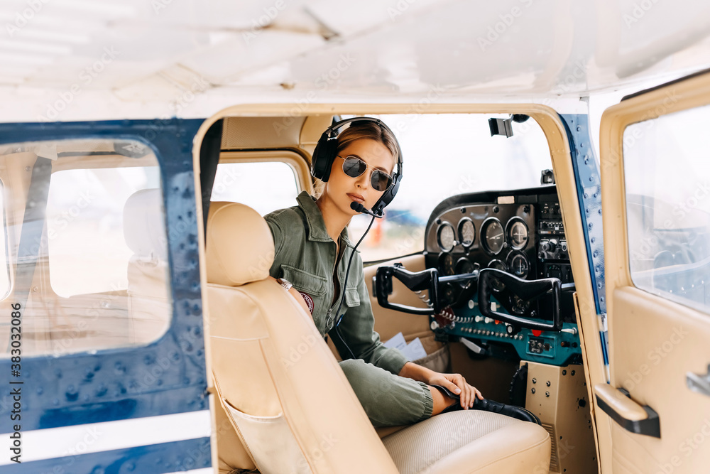 Woman pilot in private plane cockpit, wearing headset and sunglasses. Woman pilot in private plane cockpit, wearing headset and sunglasses.