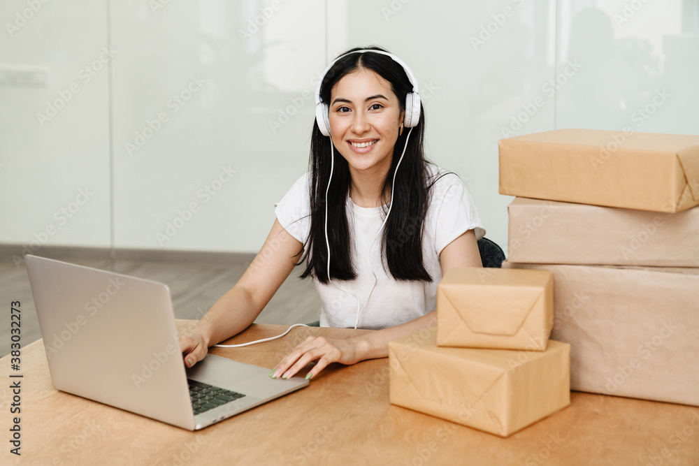 Photo of asian delivery assistance working with packages and laptop Photo of asian delivery assistance working with packages and laptop