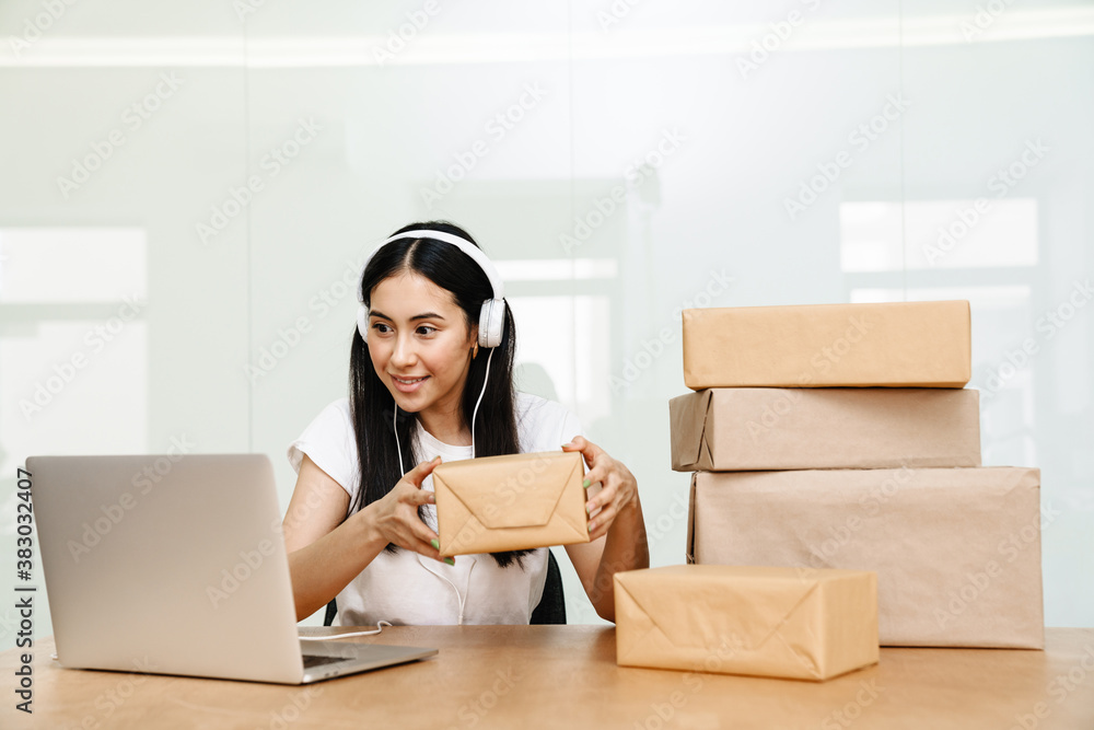 Photo of asian delivery assistance working with packages and laptop Photo of asian delivery assistance working with packages and laptop