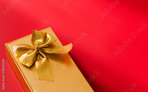 Gold color gift wrap with gold bow on red background