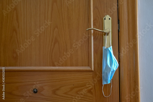 Medical face blue mask hanging on a door knob