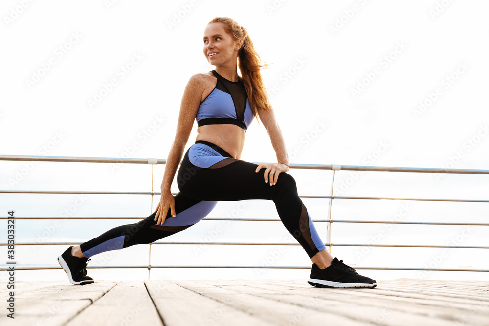 Image of redhead smiling sportswoman doing exercise while working out