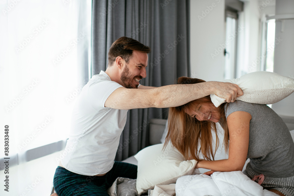 Boyfriend and girlfriend fighting pillows on the bed. Happy couple having fun at home. Boyfriend and girlfriend fighting pillows on the bed. Happy couple having fun at home.
