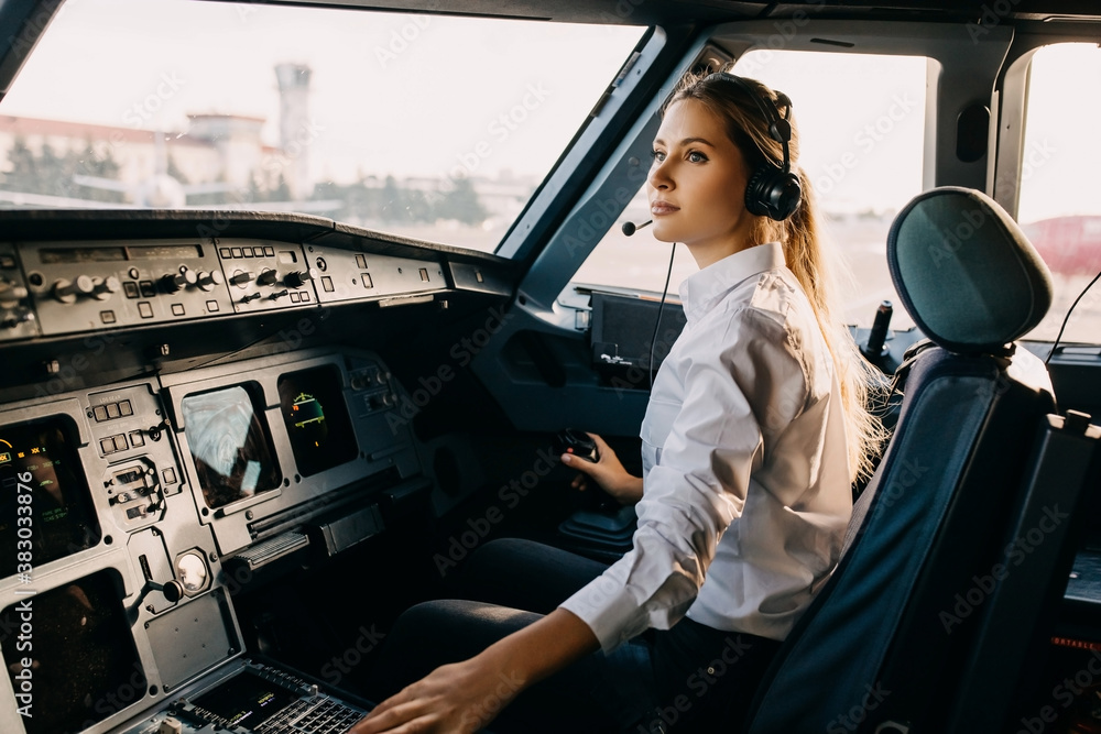 Confident woman pilot flying a commercial aircraft, sitting in cockpit. - obrazy, fototapety, plakaty 
