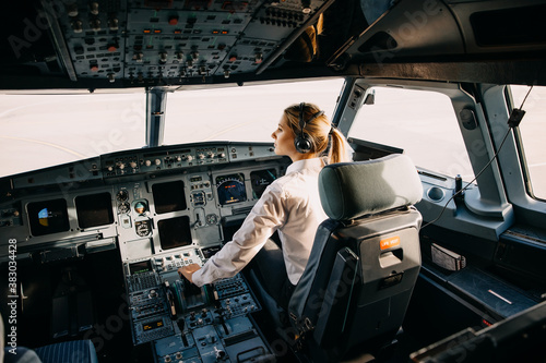 Obraz na płótnie Confident woman pilot flying a commercial aircraft, sitting in cockpit
